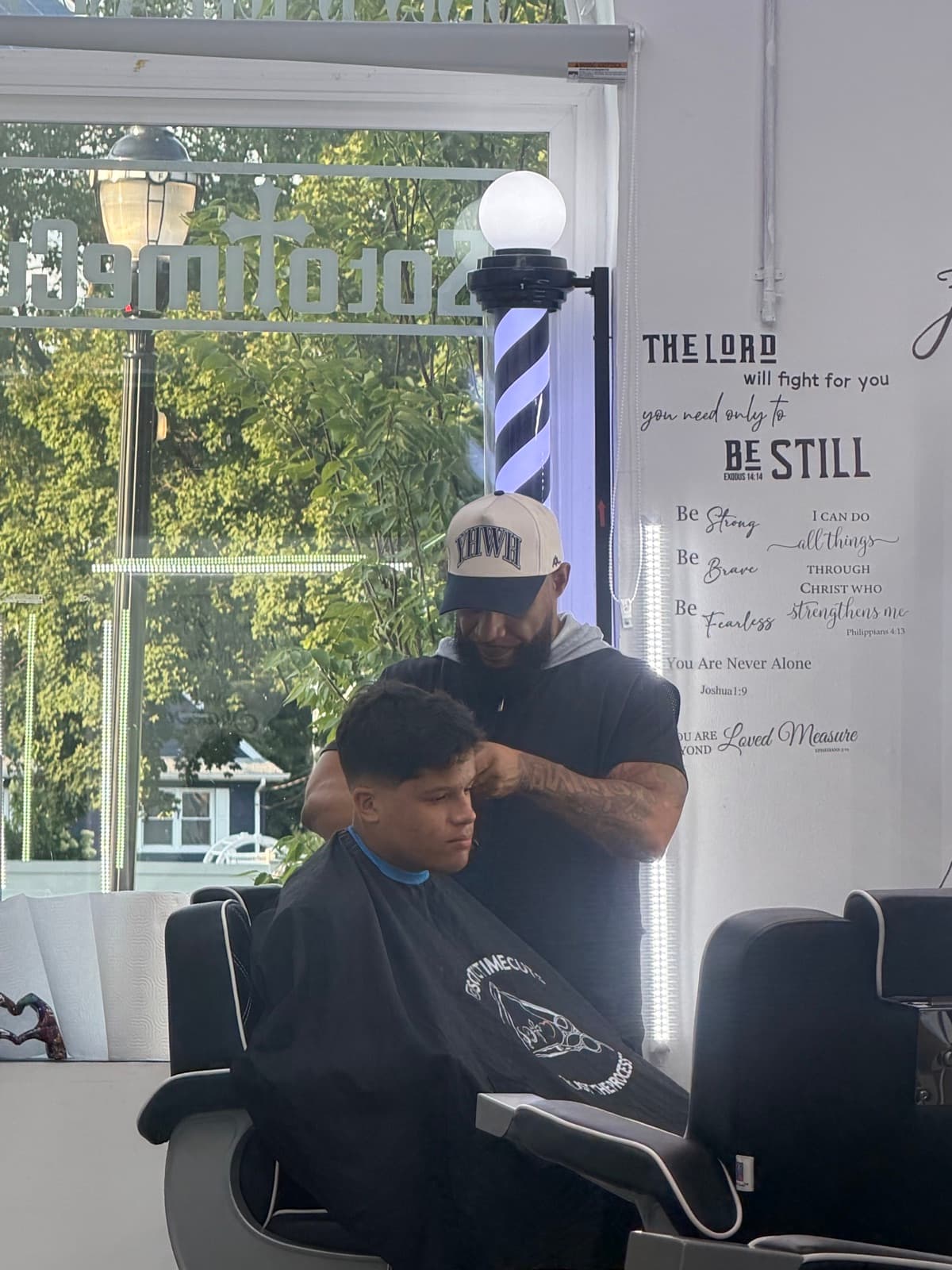 Barber finishing a taper haircut by the front window at Soto Time Cuts in Little Ferry